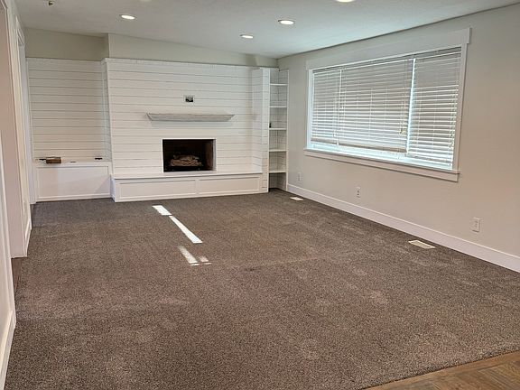 Living room with built in fireplace, and entryway with hardwood flooring.