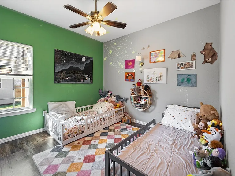 Room featuring two-tone painted walls, wood-finish flooring, a ceiling fan with integrated lighting, and a window with blinds