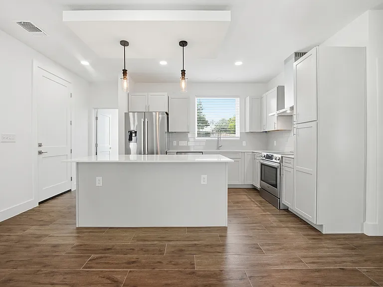 Stylish floating ceiling over the kitchen island with integrated lighting creates a warm, ambient glow and adds a striking modern architectural touch.