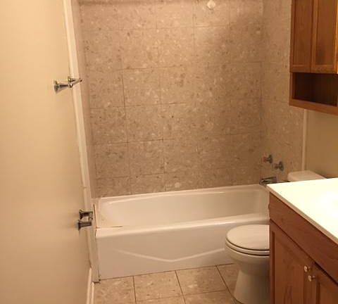 Full size bathroom with tile flooring and tile tub surround
