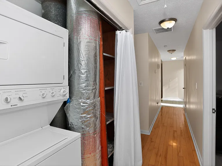 Convenient in-home laundry nook with stacked washer/dryer and built-in shelving for household storage.