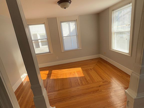 Bedroom with columns separating hall area and designed wood floors
