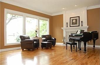 Mantel with attractive white tile is offset by a wall of windows with view of trees in backyard.