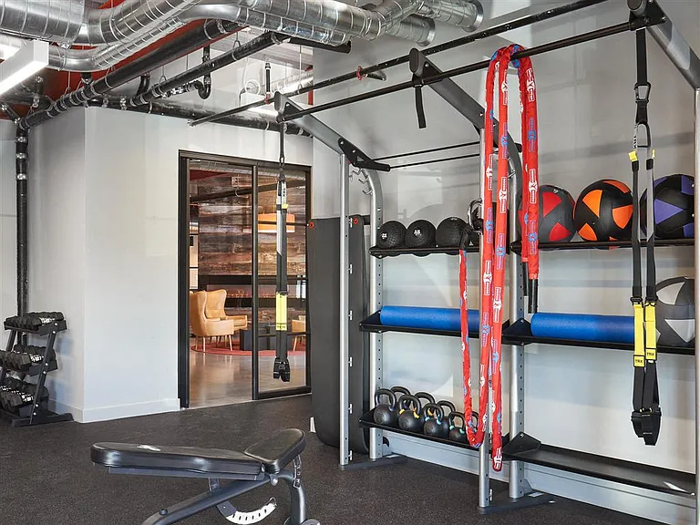 Community fitness center with dumbell rack, battle ropes, TRX straps, weighted balls, and other equipment