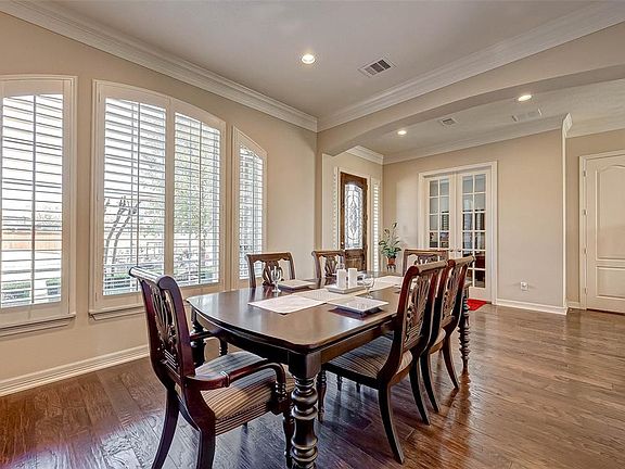 The formal dining space with custom plantation shutters will readily accommodate a larger table than shown
