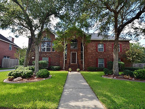 A view of the front of the home lined with mature trees framing the home.