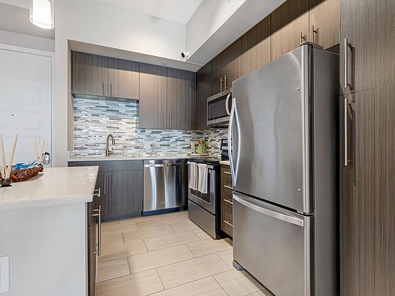 Model kitchen and dining room at our apartments in Boca Raton, featuring chairs around a table and counter seating.