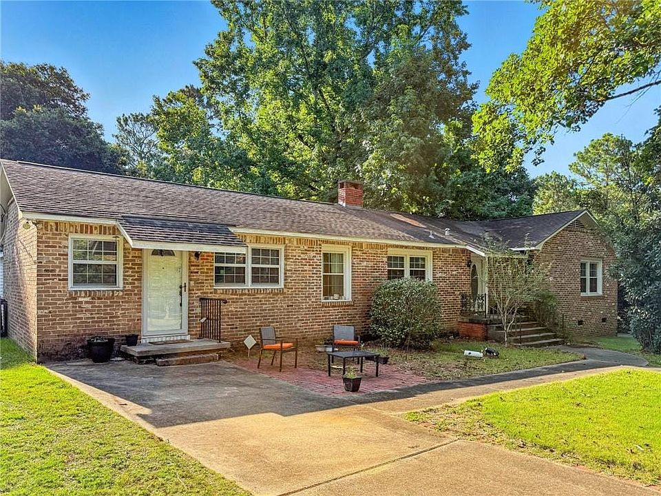 Ranch-style house with brick siding, asphalt driveway, a front lawn, crawl space, and a chimney