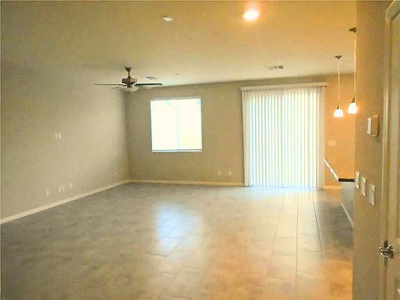The open-concept living room exudes warmth with its cozy fireplace, vaulted ceilings, and large windows framing Nevada's sunny skies. Neutral tones and plush seating create a versatile space for relaxation or entertaining, while seamless access