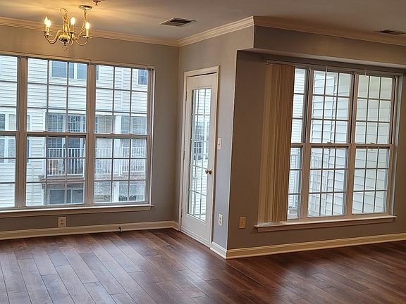 Dinning area with full sized windows, hardwood themed floors and walk out door to balcony
