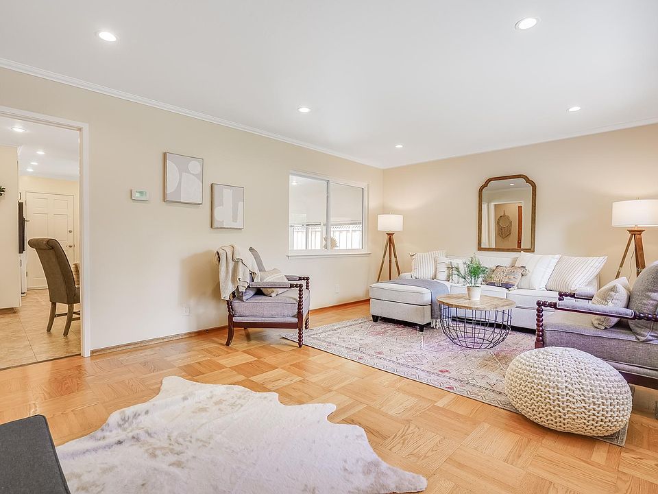 Spacious living room with a large window and recessed lighting. Beautiful crown moldings and hardwood floors elevates the room.