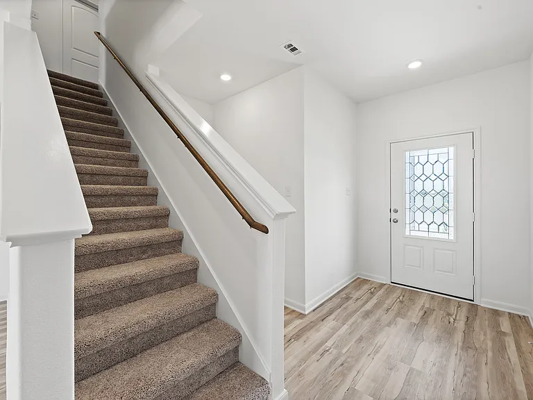 Spacious foyer with carpeted stairs.
