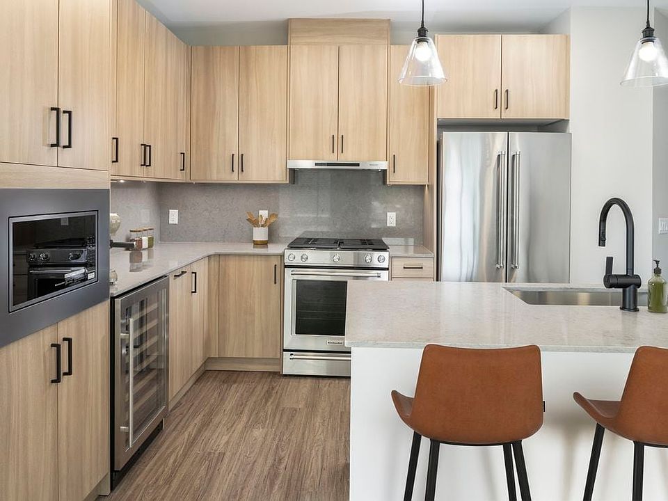 Signature Collection kitchen with stainless steel appliances (wine fridge included), quartz countertops, quartz tile backsplash, oak cabinetry, and hard-surface flooring