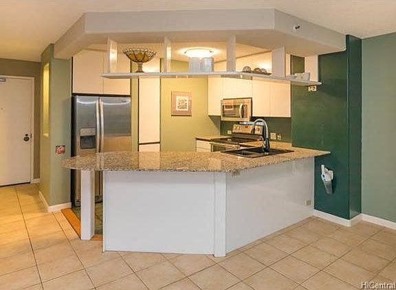 Open kitchen with granite counters and stainless steel appliances. Tall pull out pantry next to Fridge. Appliances are newer.