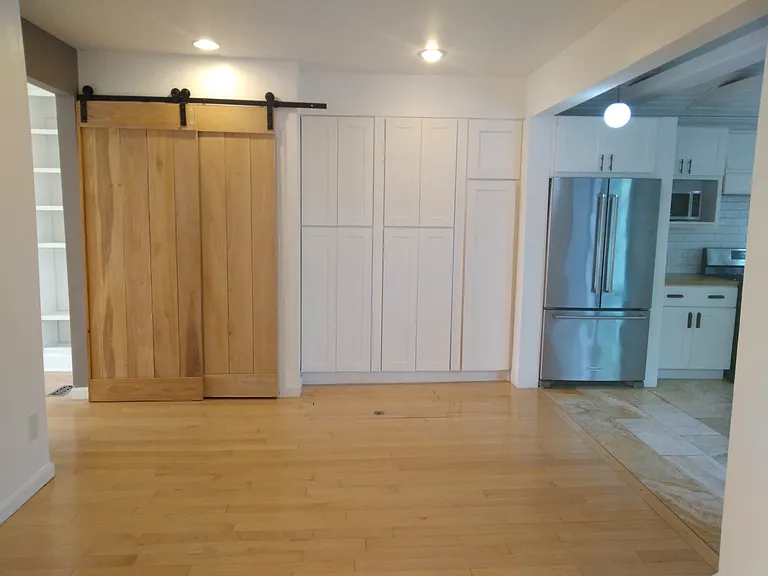 View of dining room facing the washer/dryer (behind sliding barn doors) and storage cabinets.