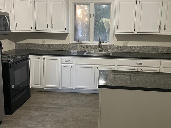 Kitchen with granite countertops, island, stove, microwave and stainless steel double door fridge!