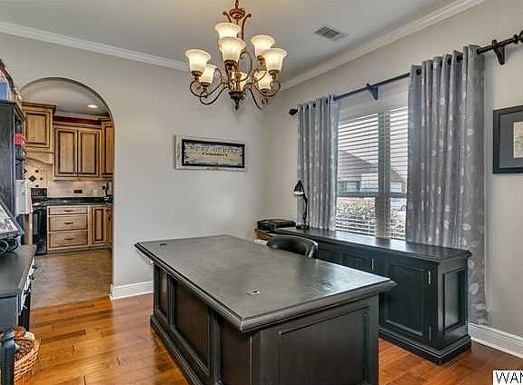 To the right of the foyer is the formal dining room with chandelier, arch opening into the kitchen, and hardwood floors.