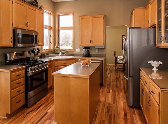 The kitchen has high-end stainless appliances and large corner windows for a view of the private back yard and playset.