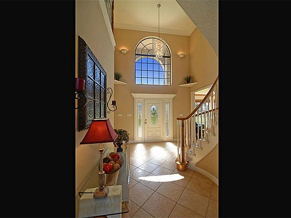 Guests enter the home thru this leaded glass front door into the Foyer which offers tile floors, an arched window that lights naturally, crown molding and a 2-story ceiling that provides drama