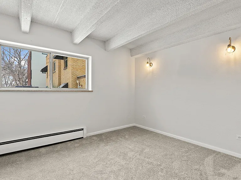 Bright and inviting room with cozy carpet, stylish wall sconces, and a scenic view from the window, perfect for a tranquil living space.