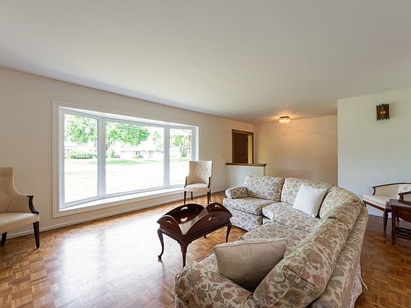 Spacious living room with large window and parquet hardwood floor.