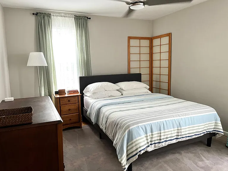 Bedroom with queen bed, soft cotton sheets and nice area rug over wooden floors.