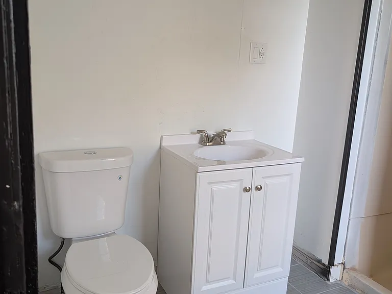 Bathroom view of the new toilet and vanity without the AI generated mirror.