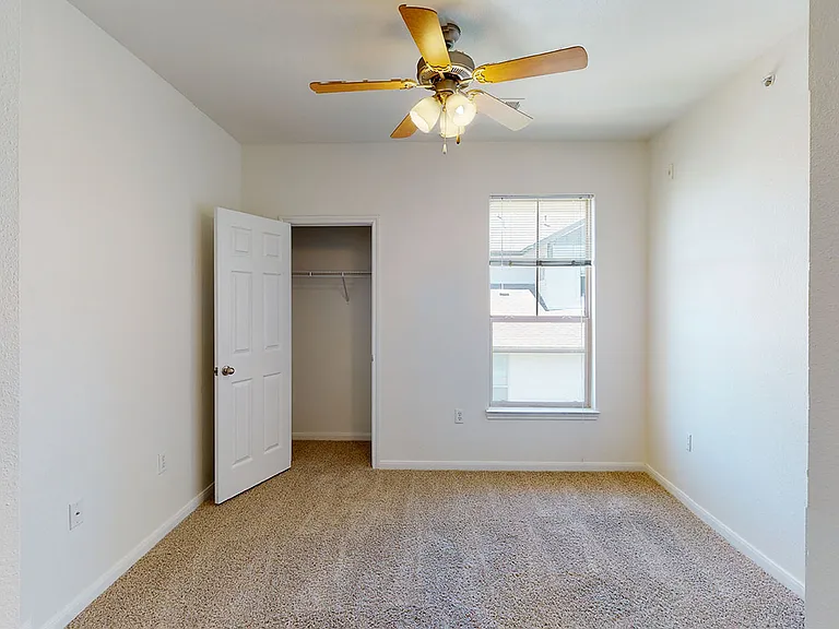 Spacious apartment bedroom with plush carpet flooring.