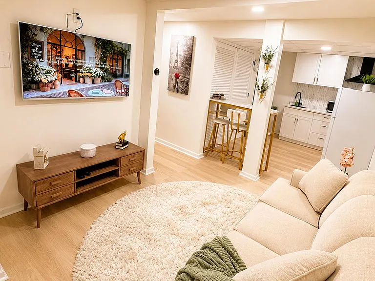 Comfortable living area with a sectional sofa, media wall, and easy flow into a breakfast bar and updated kitchen.
