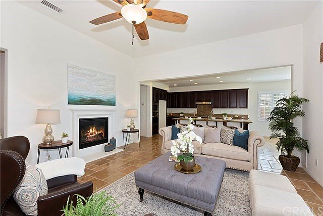 The kitchen opens to the family room with a raised hearth fireplace and ceiling fan light