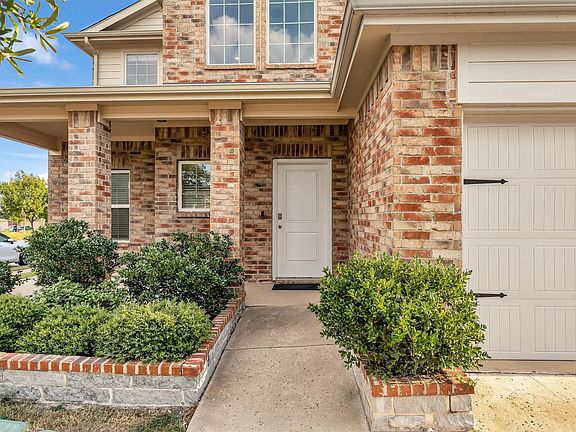 Brick exterior with an integrated garage, covered entry, and decorative shrubbery