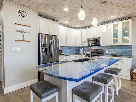 Lots of artistic flair, backlit upper cabinet metal sculpture, real stone island counter top, small creative touches throughout...