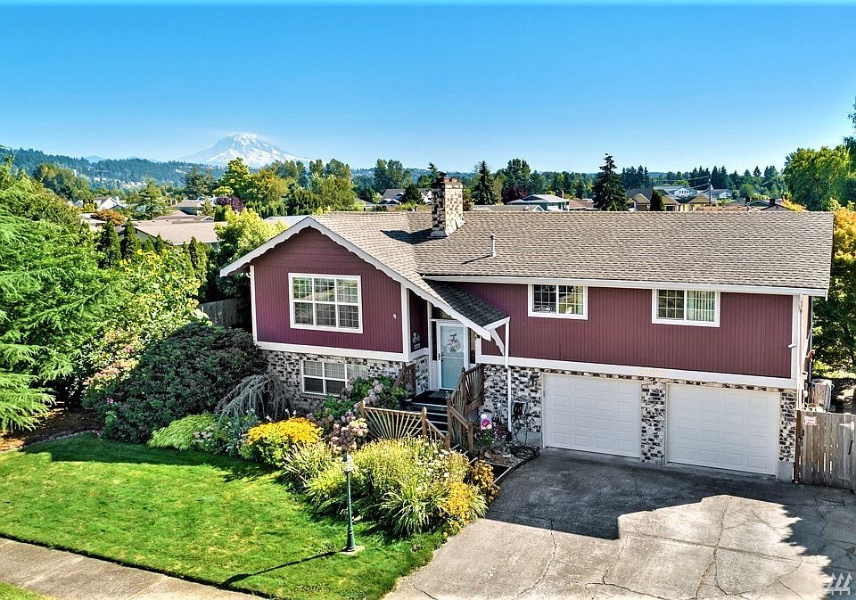 Front view of amazing landscaped yard and the view of Mt Rainier from the back of the house under the covered deck and from master bedroom!