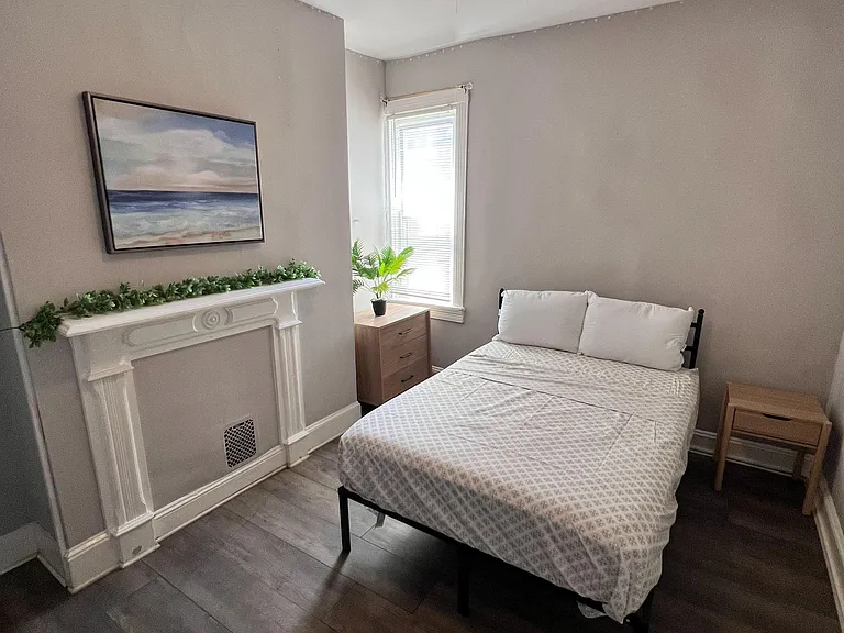 Furnished bedroom with a ceiling fan, hardwood-style flooring, and a window with blinds plus a nightstand and dresser.