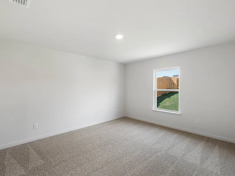 The spacious master bedroom has a large window that lets in natural light and backyard views.