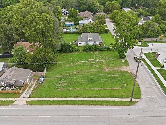 Expansive undeveloped lot featuring a grass surface, mature trees, and street frontage