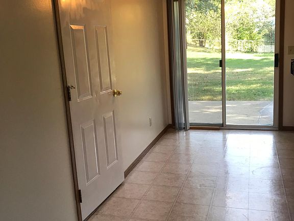Eat-in kitchen from living room, showing garage door, and sliding glass doors with new vertical blinds to backyard patio.