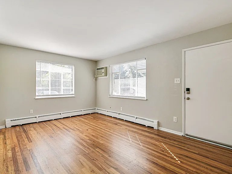 Bright and airy living room with sleek hardwood floors, large windows, and modern touches.