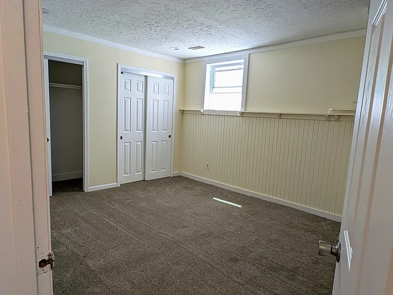 Large master bedroom with brand-new carpet, multiple closets, and a wide window for natural light.