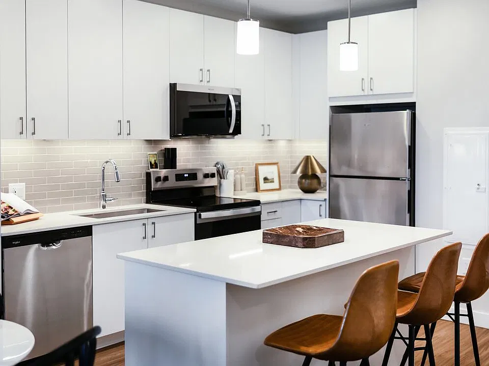 Design Collection I kitchen with stainless steel appliances, white cabinetry, grey tile backsplash, under-cabinet lighting, white quartz countertops, and hard surface flooring
