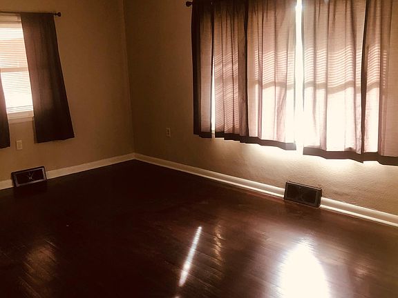 Living room is furnished with blinds and curtains/rods.