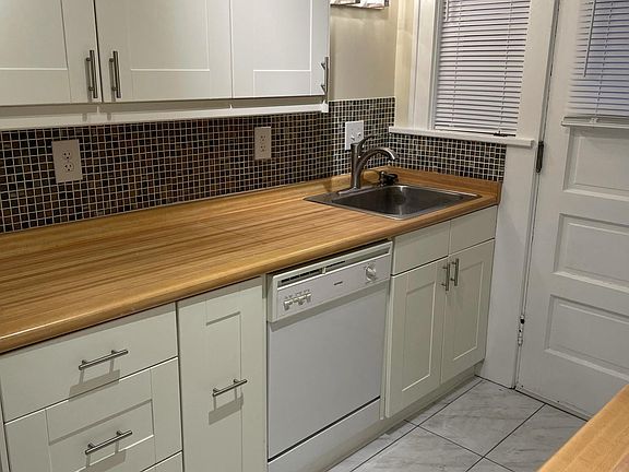 Kitchen with new flooring, glass tile backsplash, dishwasher, and disposal.
