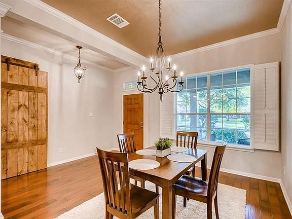 Come on in and sit down! This formal dining area offers decorative painted  ceilings, crown molding, shutters and gleaming hardwood floors.  Note the sliding barn door to the left.  And the transom window over the front door.
