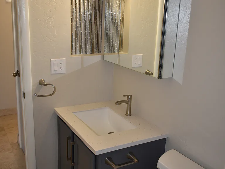 Hall Bathroom - Solid-surface countertop, sink, mirrored vanity cabinet, light fixture, faucet and fixtures installed Aug 2024
