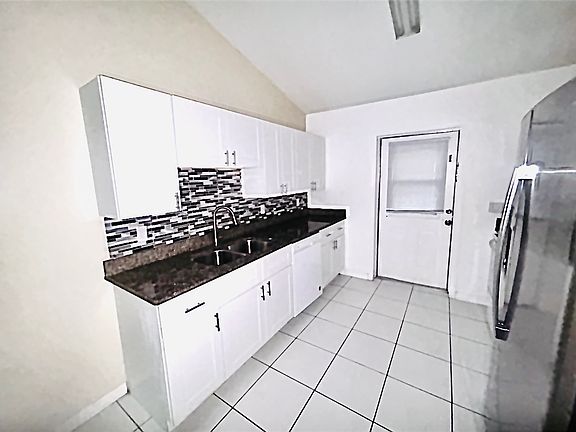 Picture of kitchen sink with granite countertops, new cabinets, and nice glass mosaic backsplash