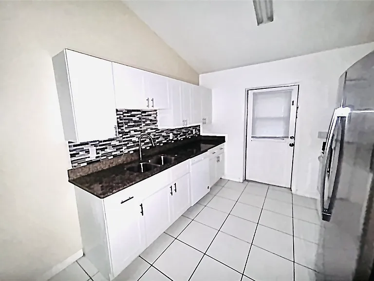 Picture of kitchen sink with granite countertops, new cabinets, and nice glass mosaic backsplash