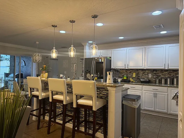 Modern open-concept kitchen with granite countertops, stainless steel appliances, and spacious breakfast bar seating.