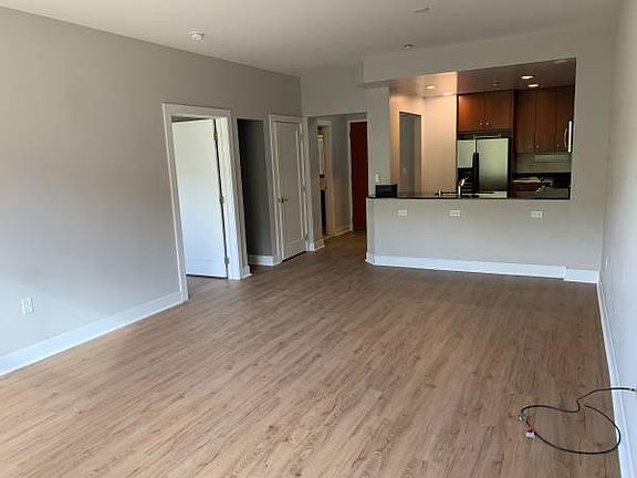 standing in living room looking towards entry and kitchen. Extra closet space and bedroom door on left side