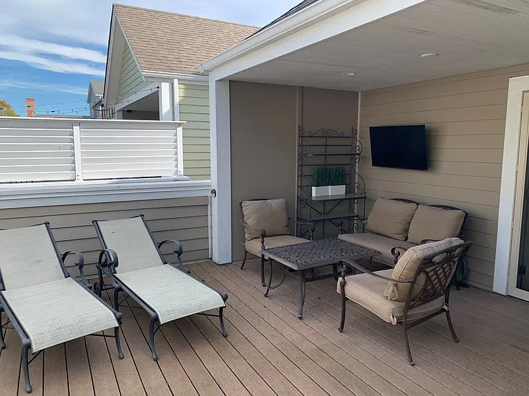 Rooftop Deck with lunger seating and outdoor TV. Note privacy screen to neighbor.