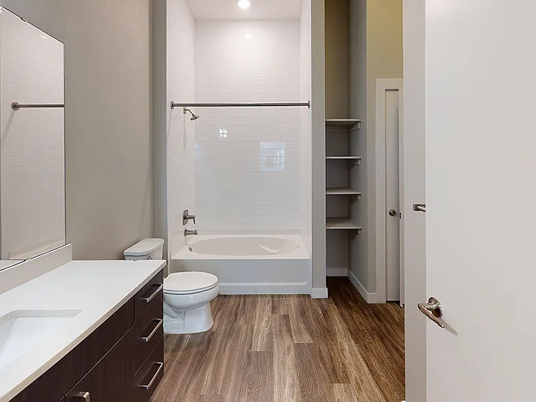 Apartment bathroom with large soaking tub and wood-style flooring.